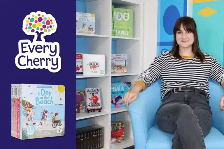 A woman sits in a blue chair next to shelves of children's books, fostering audience engagement. The Every Cherry logo and a book box set titled "A Day at the Beach" are displayed on the left.
